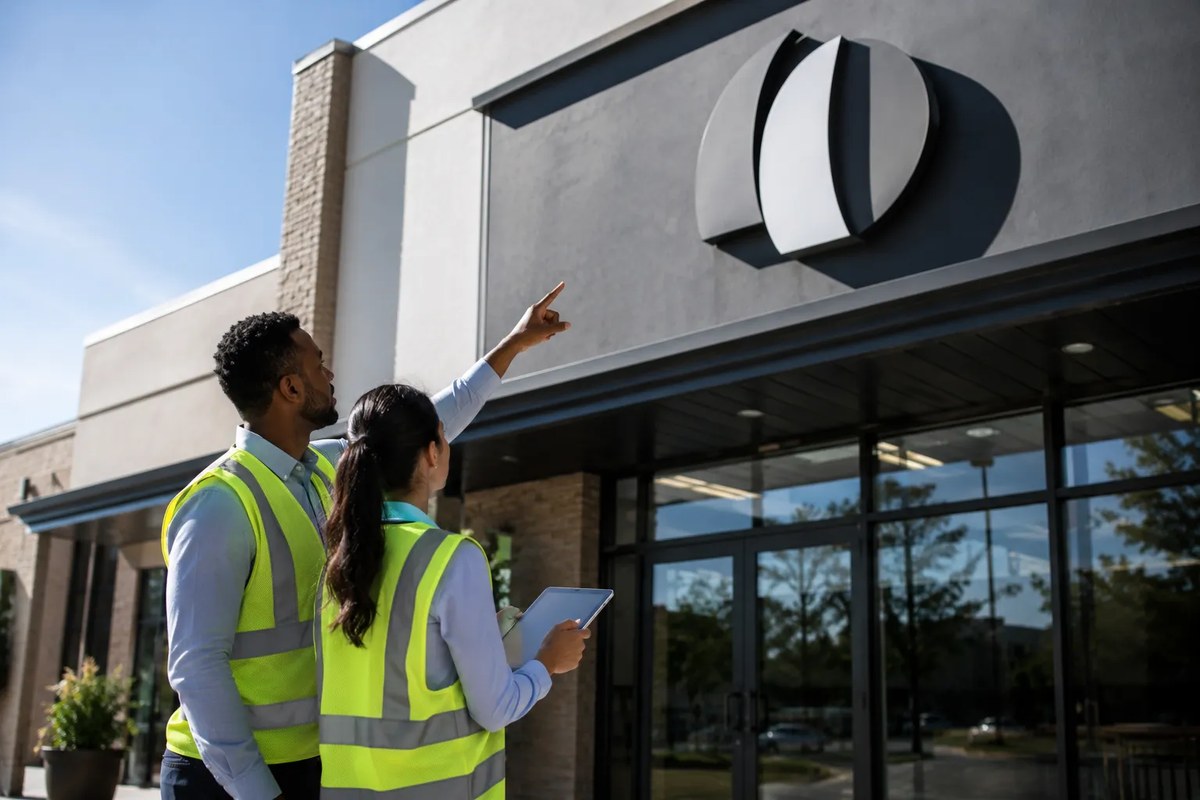 Facilities professionals safely observing a business sign from ground level