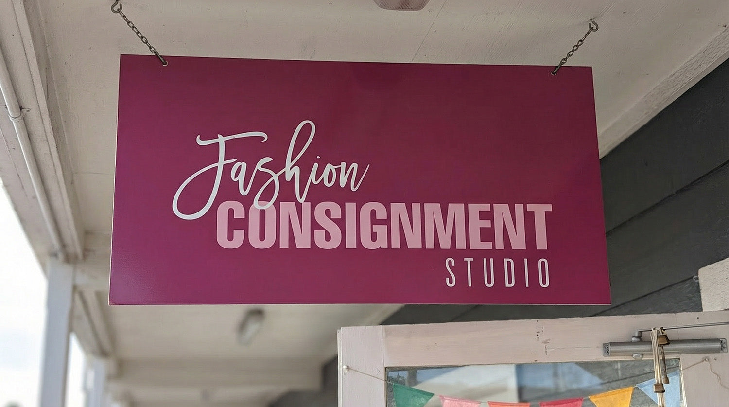 Hanging blade sign for Fashion Consignment Studio projecting over a sidewalk entrance